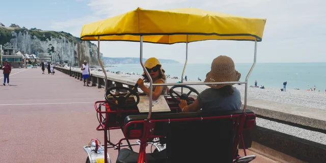 2 petites filles avec des chapeaux à bord d'une rosalie, voiturette à pédale, le long de l'esplanade de Dieppe, face aux falaises et à la mer