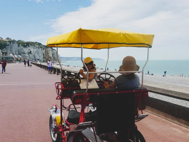 2 petites filles avec des chapeaux à bord d'une rosalie, voiturette à pédale, le long de l'esplanade de Dieppe, face aux falaises et à la mer