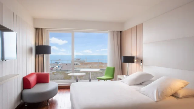 Une chambre d'hôtel raffinée et claire avec une baie vitrée vue sur la mer