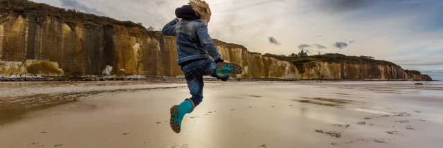 Un enfant saute sur la plage de Varengeville à marée basse devant les falaises