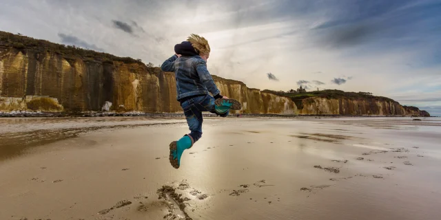 Un enfant saute sur la plage de Varengeville à marée basse devant les falaises